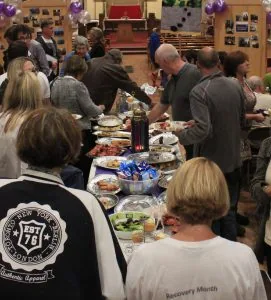 People gathered around food and conversation at a Recovery Cymru community event.